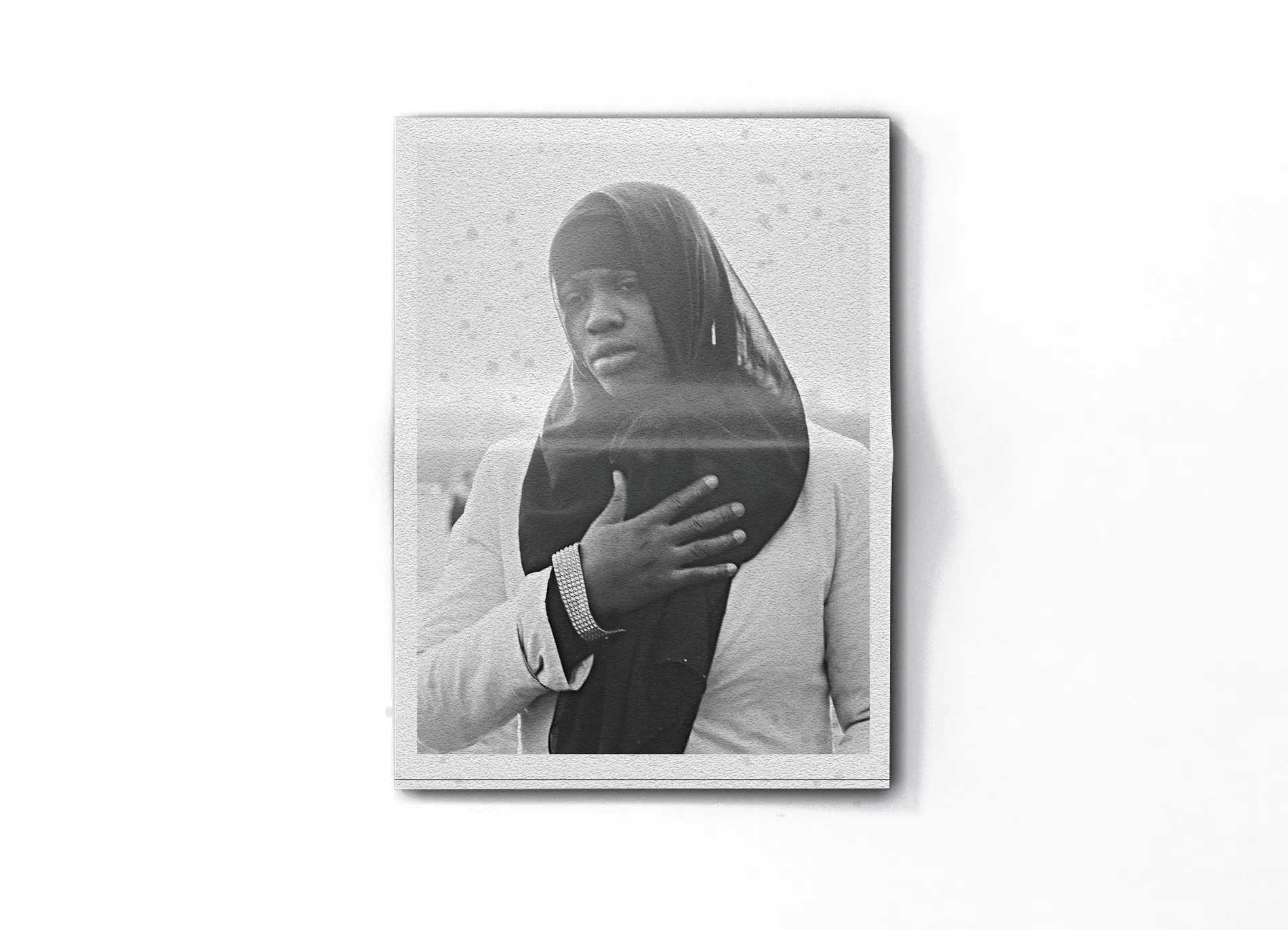 The back of the folded newspaper on a white surface: a woman in a headscarf with her hand on her chest.