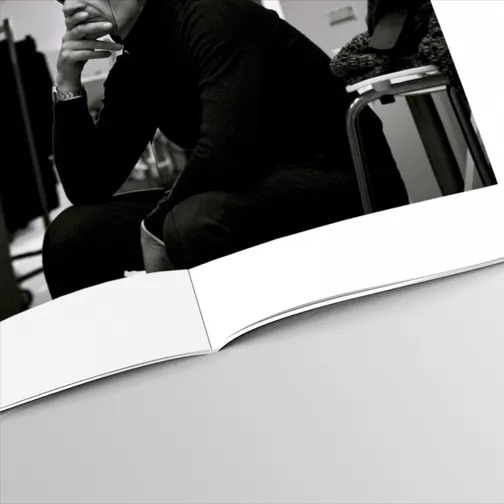 Close-up of the open book: a black and white photograph of a model in a black sweater, hand at his chin, printed across the page.