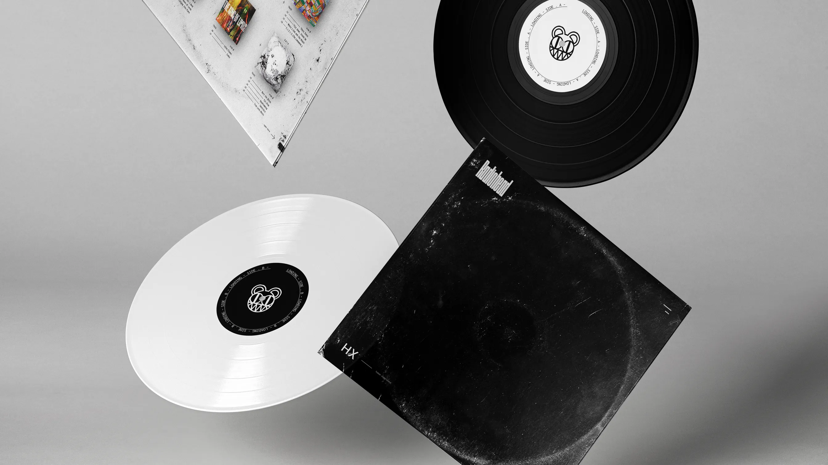 Two black records, a white record and the HX sleeve falling through the air on a white background.