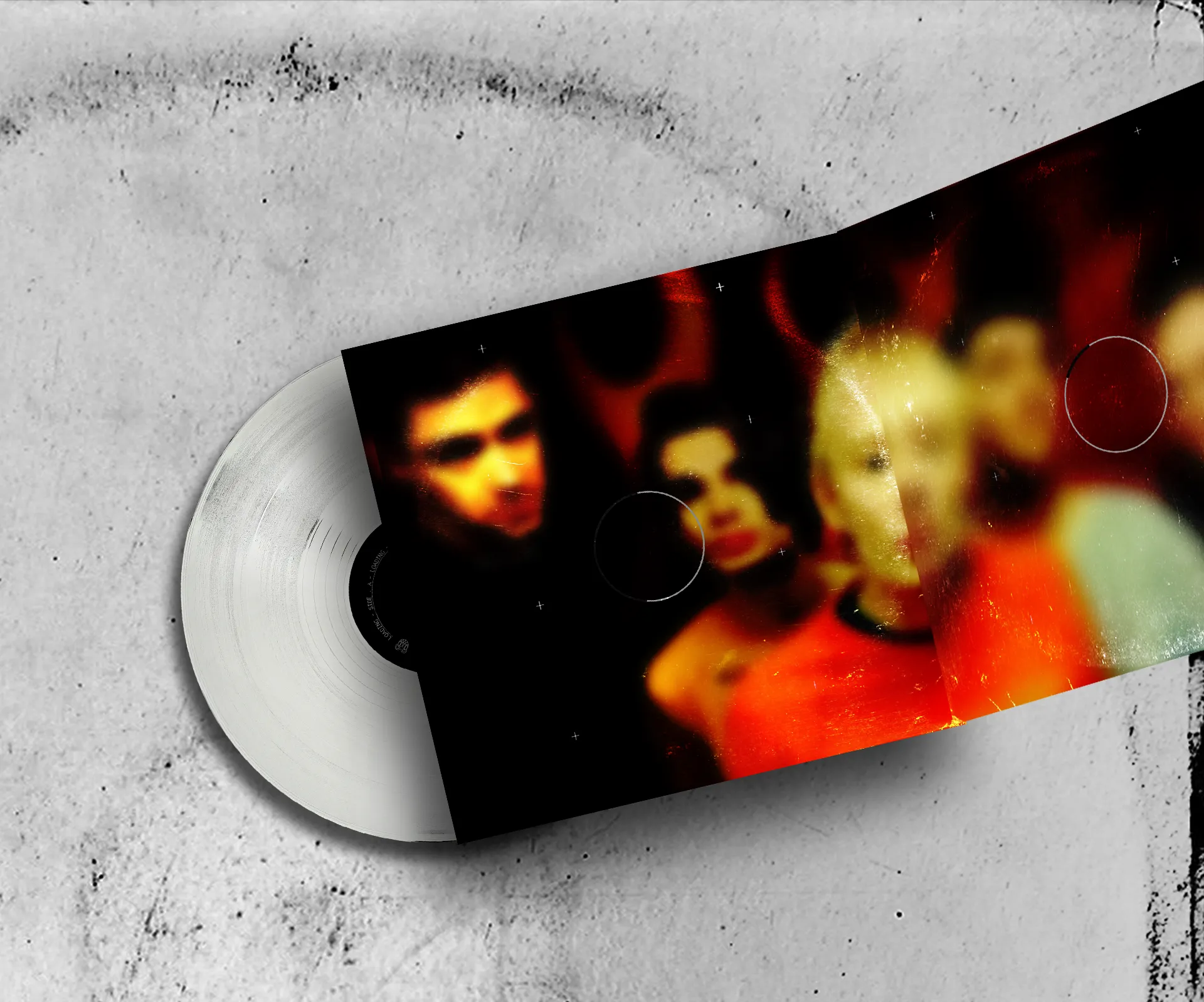 The open gatefold with the blurred band photo, and a white record slipping out, on a scratched white surface.