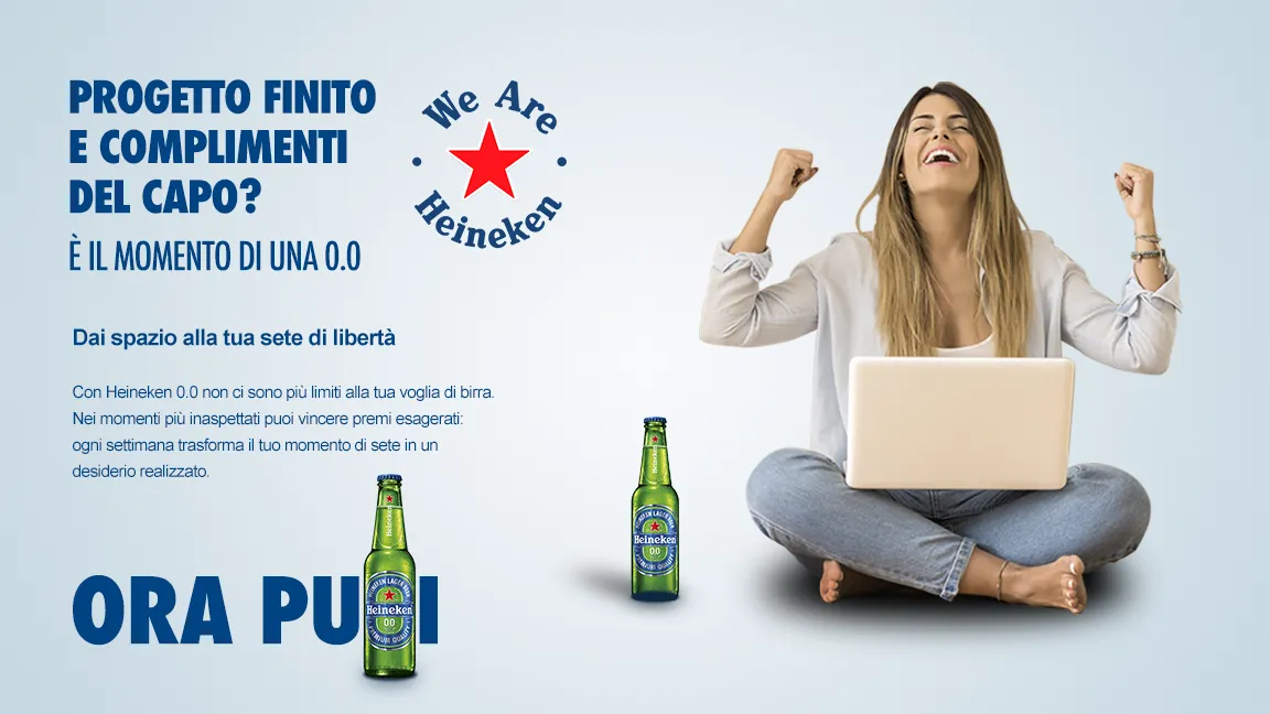A woman cheering at her laptop with a Heineken 0.0: “Project done and compliments from the boss? Now you can.”