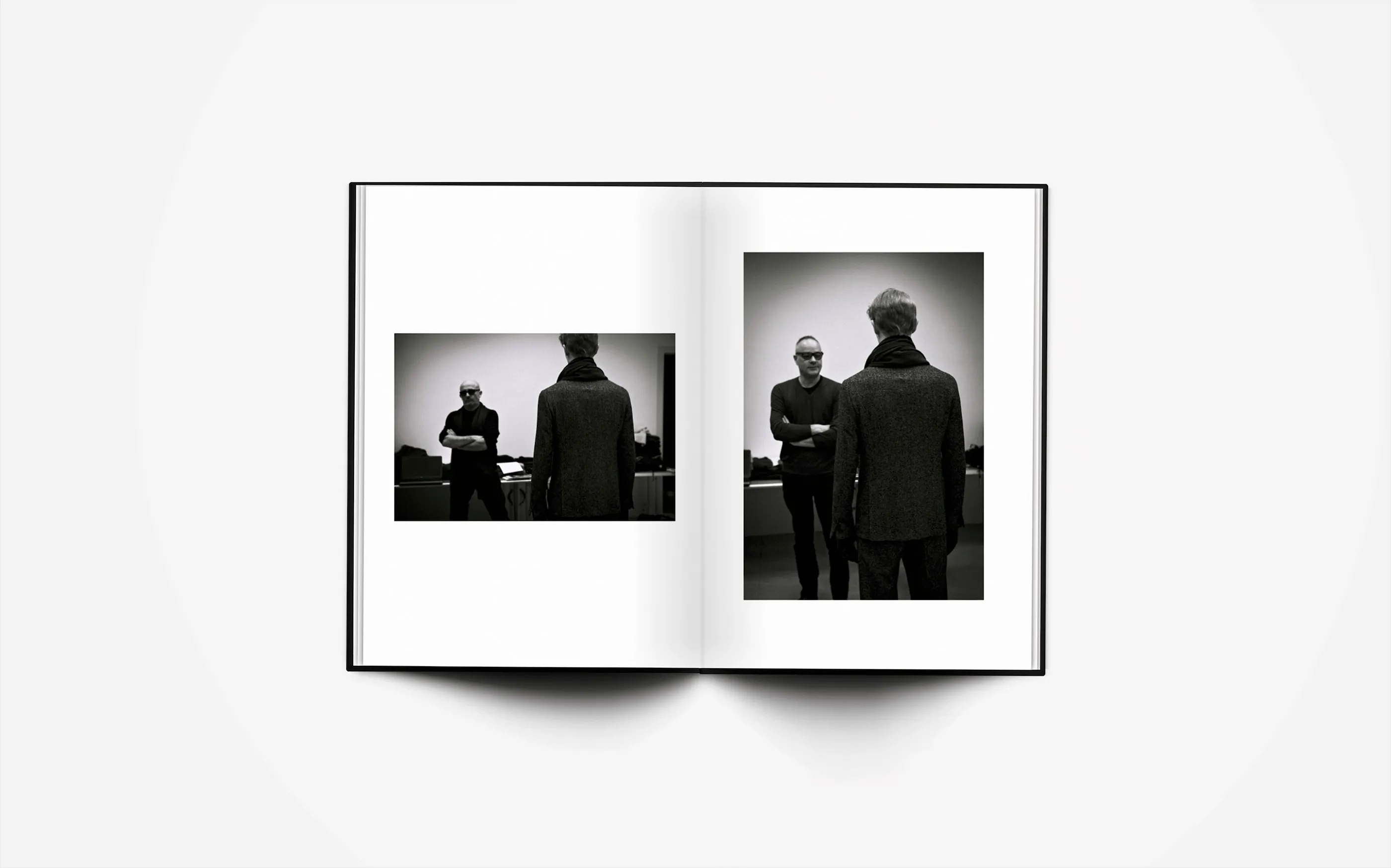 Open spread: two black and white photographs of models seen from behind, standing against a plain wall.