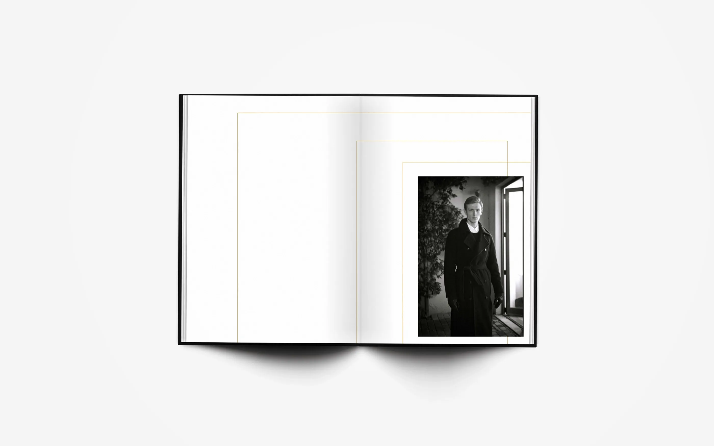 Open spread: a single portrait of a model in a dark coat by a window on the right page, thin gold lines on the left.