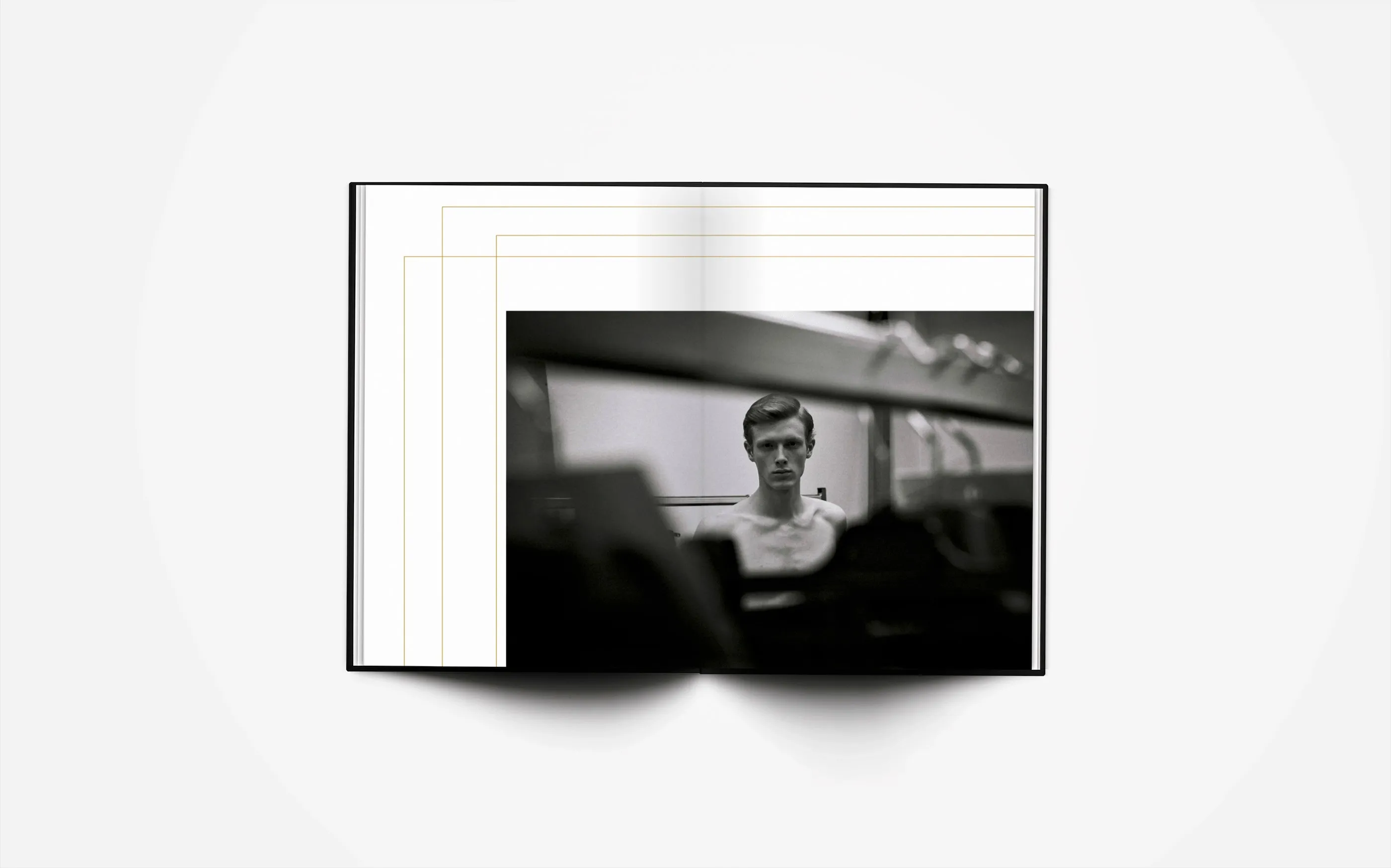 Open spread: a wide backstage photograph of a model at a table, framed by nested gold lines.